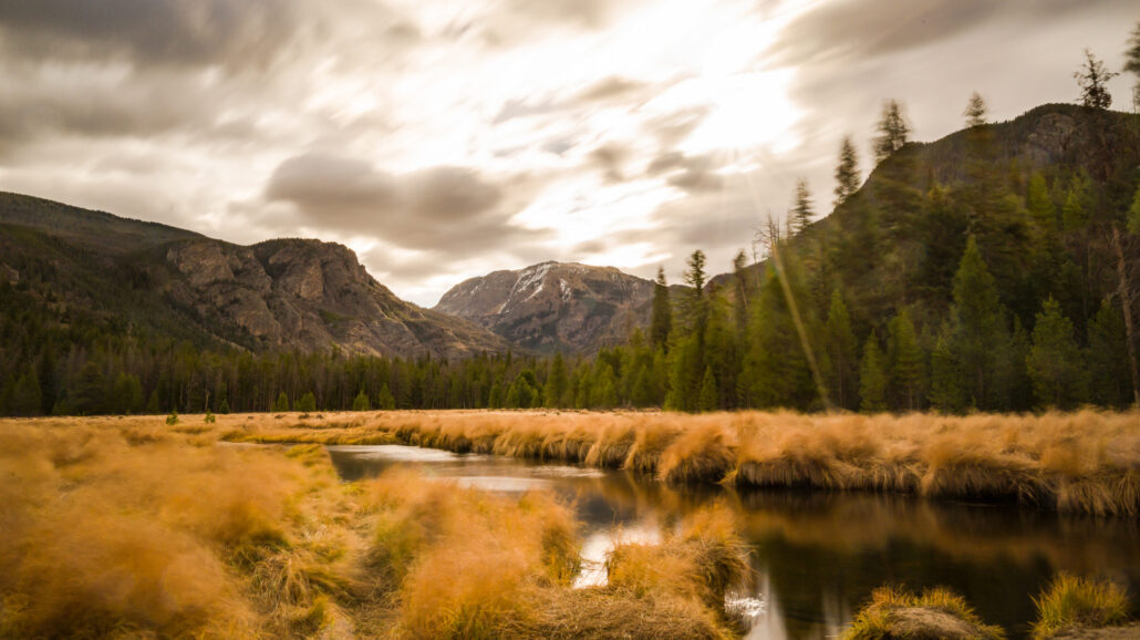 Mt. Craig was seen under the fast moving clouds at the East Meadow in Rocky Mountain National Park in Colorado on a windy autumn day. The strong gusts of wind knocked trees back and forth, causing eerie creaking sound coming out of the trees.