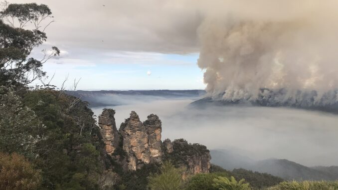 The iconic rock formation, Three Sisters, overlook the bushfires at Mount Solitary at Blue Mountains National Park.