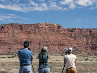 Three people observe condor release pens through cameras, scopes, and binoculars during the 28th annual California condor release event at the Vermilion Cliffs National Monument on National Public Lands Day on Saturday, Sept. 28, 2024.
