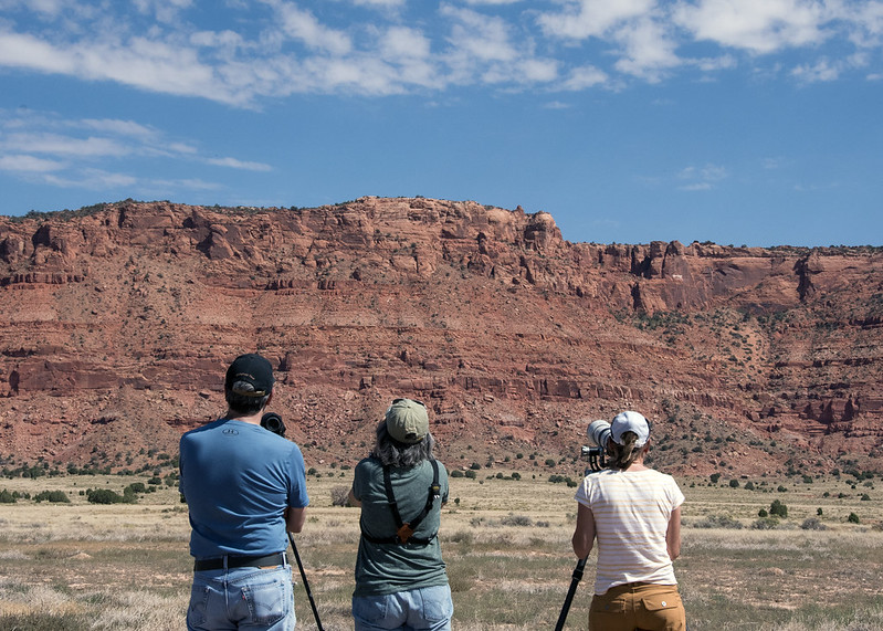 Three people observe condor release pens through cameras, scopes, and binoculars during the 28th annual California condor release event at the Vermilion Cliffs National Monument on National Public Lands Day on Saturday, Sept. 28, 2024.